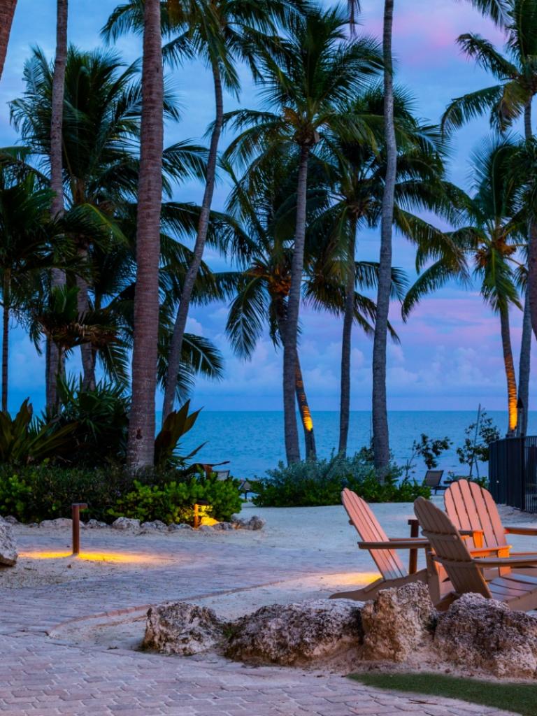 A sunset at Amara Cay with a firepit and chairs.