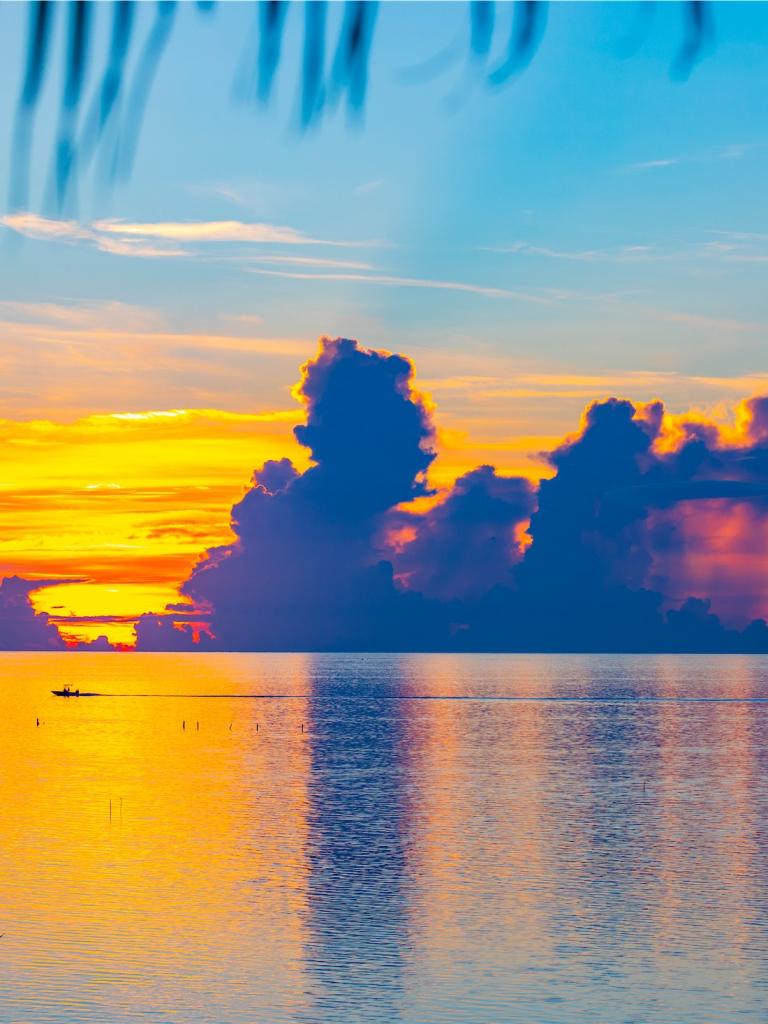 boat sailing across the ocean at sunset