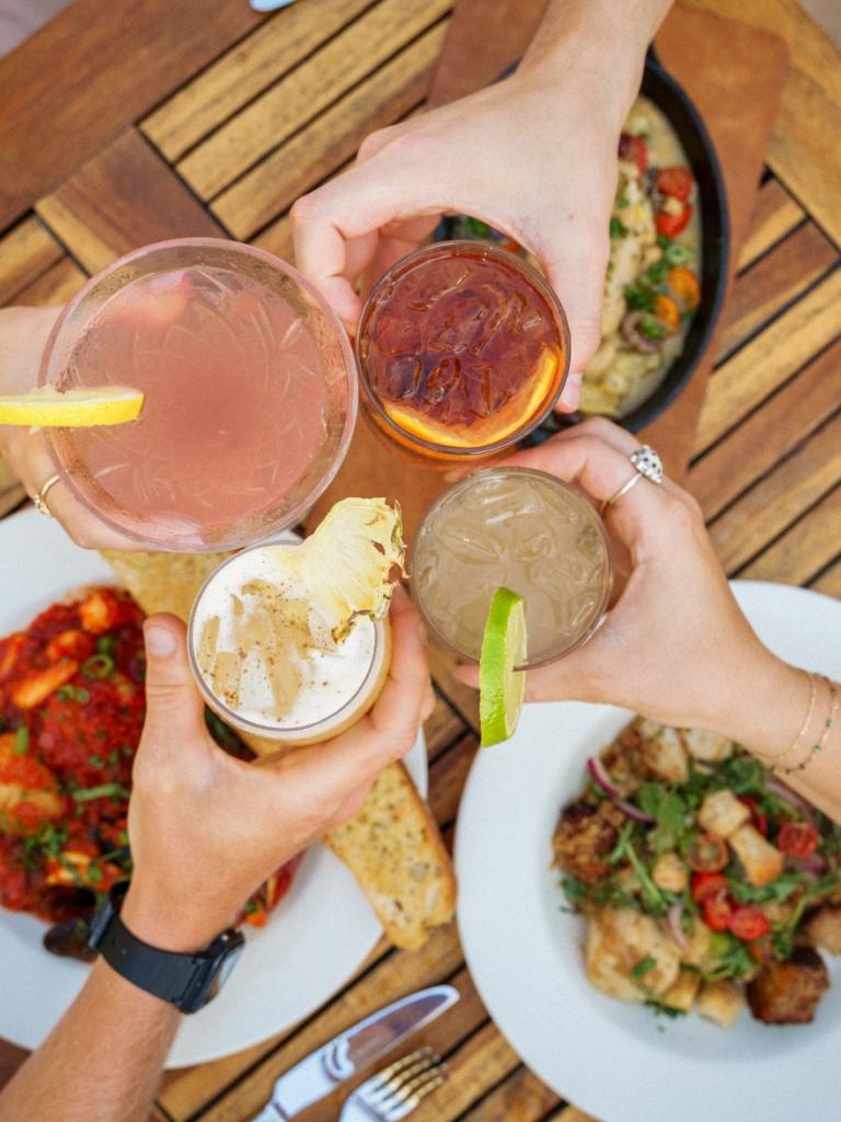 People cheers their drinks over a table of food at ReelCatch for dinner.