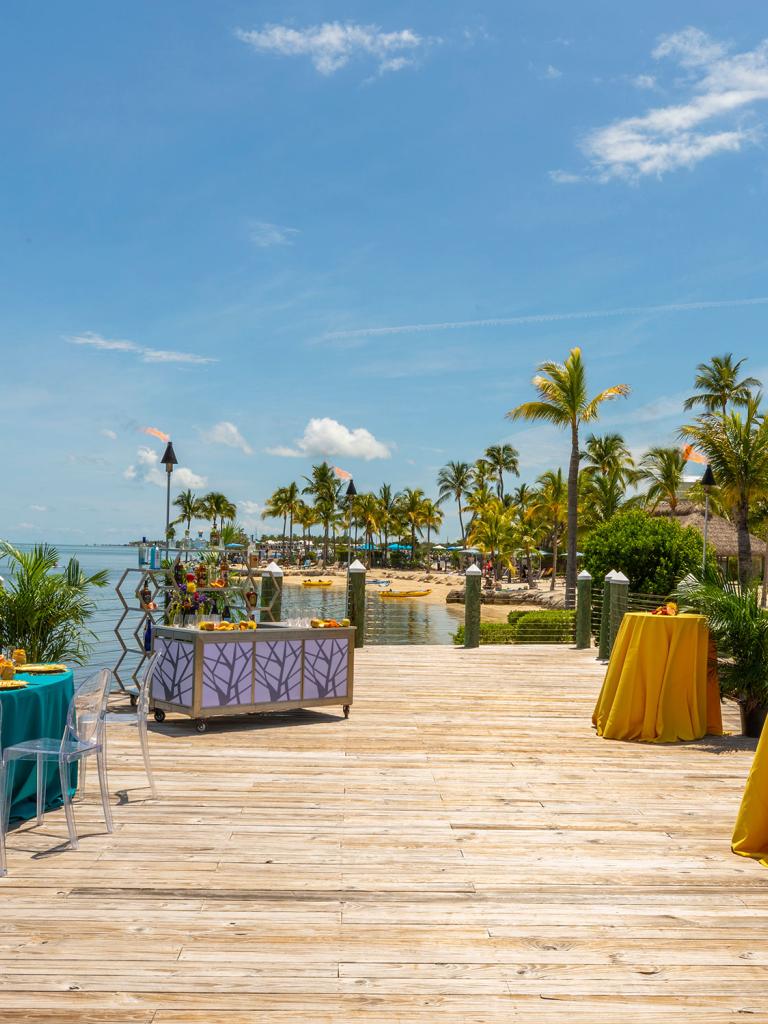 Long wooden pier set for an even with colorful tables. 