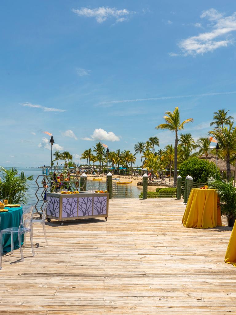 Long wooden pier set for an even with colorful tables. 
