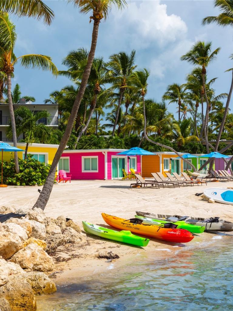 canoes on shore by the colorful cottages on the beach