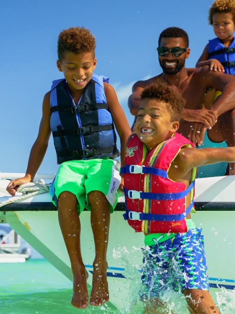 family jumping off a boat into the ocean