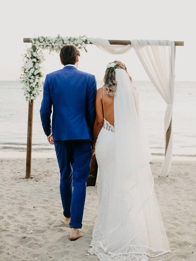 bride and groom walking towards an alter on the beach