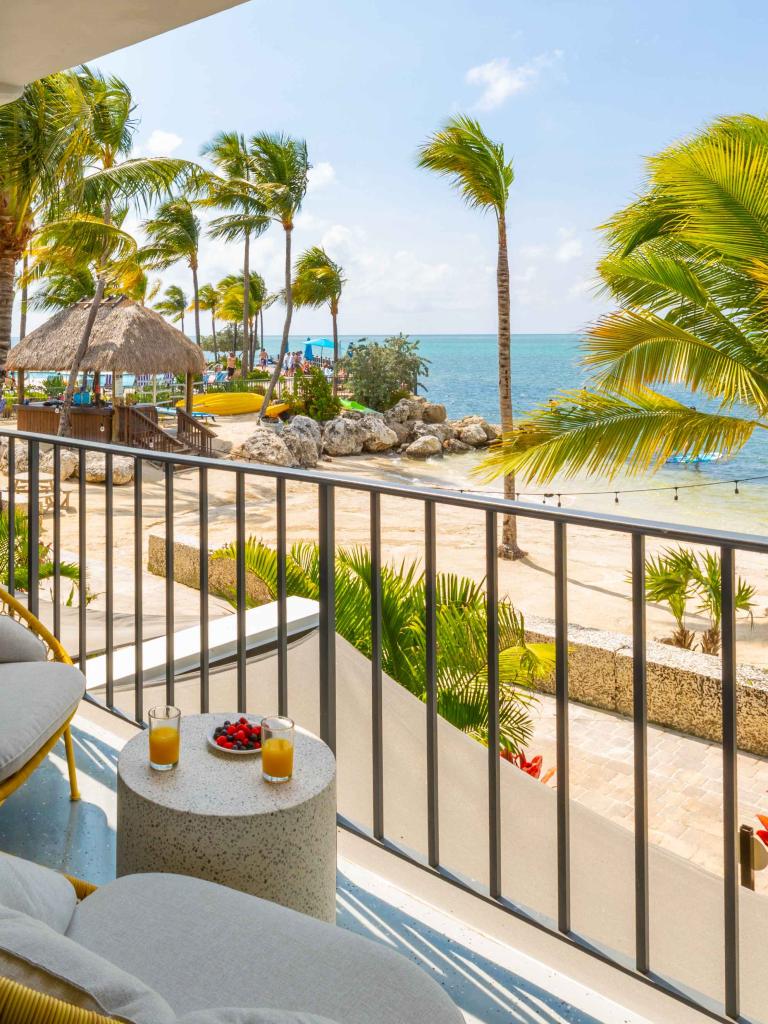 View from a hotel balcony overlooking the beach, palm trees, and the ocean.