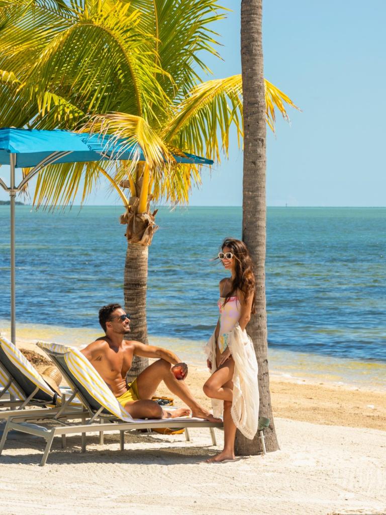 A couple smiles at each other while on a beach at Three Waters Resort