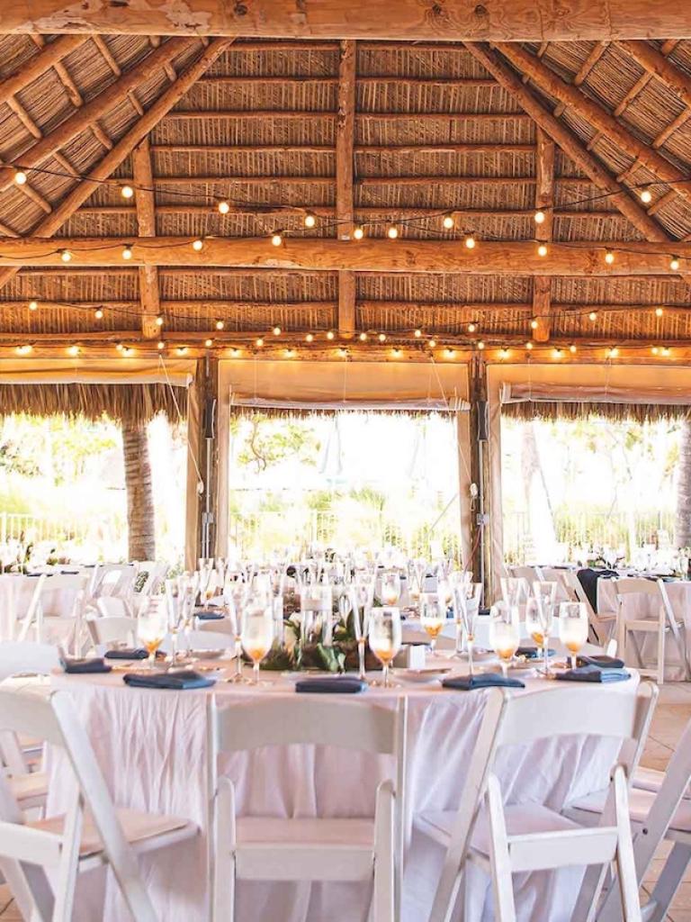 wedding tables set up for a wedding under a large tiki