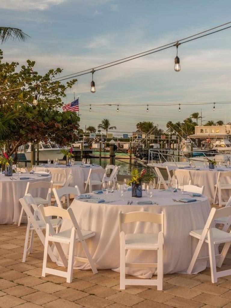 Outdoor patio set up with white tables and chair's for an event.