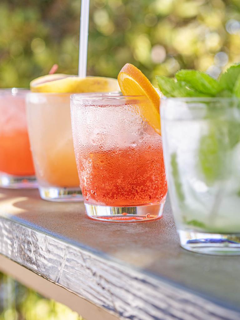 four cocktails on a railing with the ocean in the background