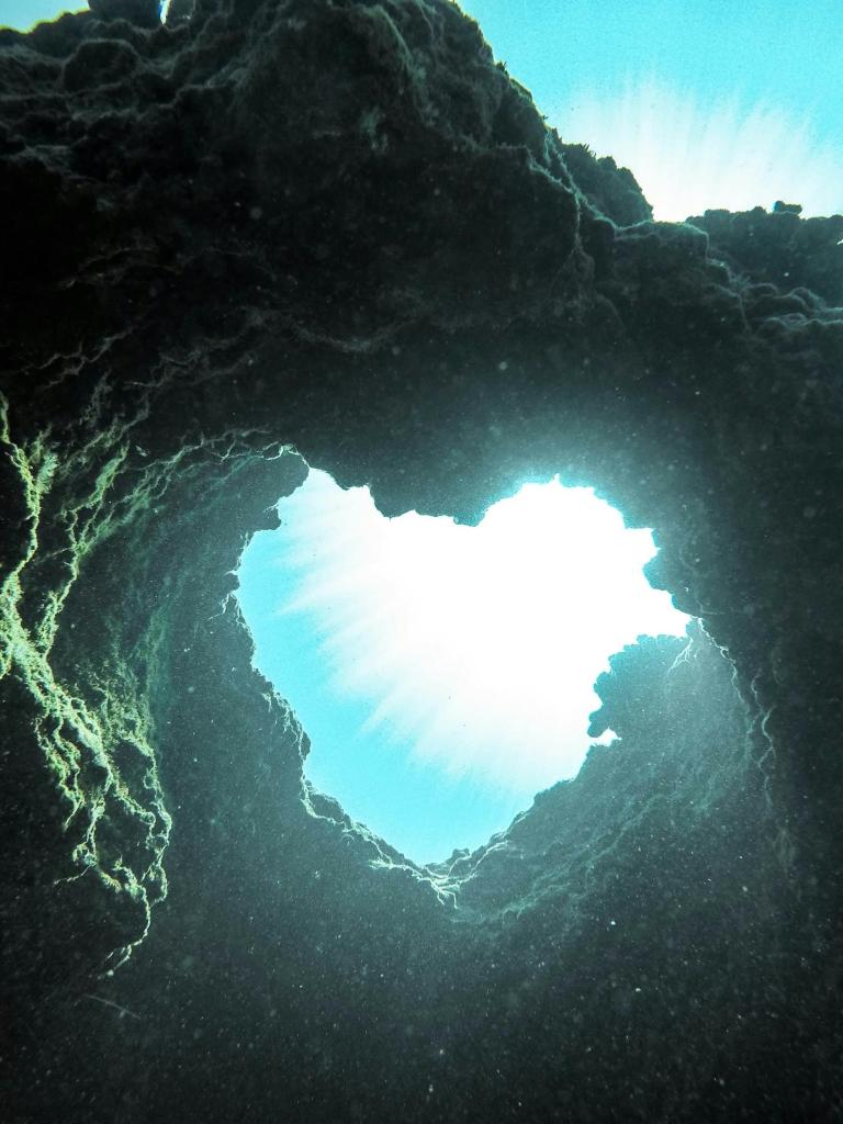 A heart shape out of a rock in the ocean.