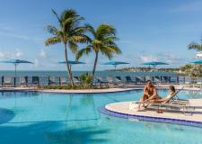 A couple sitting by the pool on chaise lounges.
