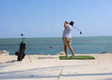 Man hitting golf balls into the ocean