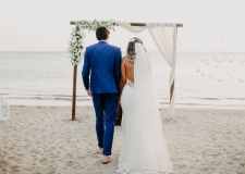 bride and groom walking towards an alter on the beach