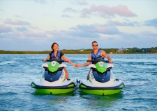 a couple holding hands while on separate jetskis