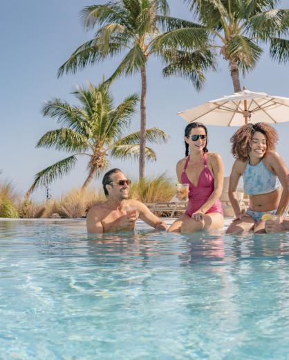 Friends sit by the pool on a sunny day at Amara Cay